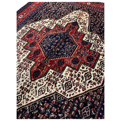 Rug with a central medallion and bold pattern in dark blue, red, and beige.