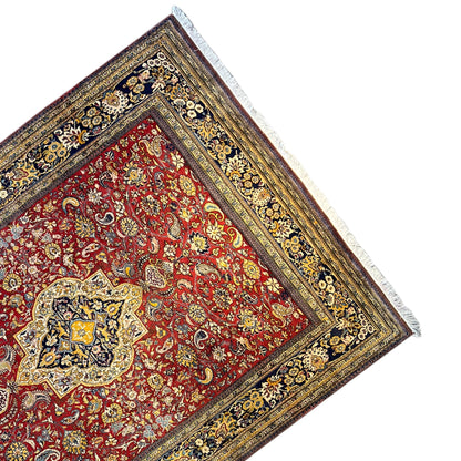 Shahreza carpet detail from an angle: red medallion in a blue-and-gold border frame