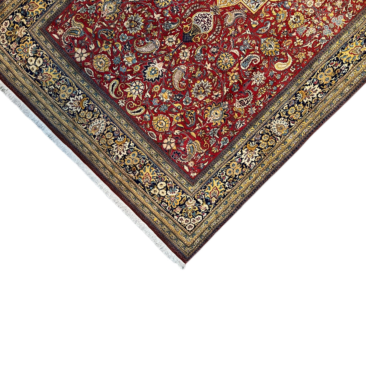 Shahreza carpet corner view with a red ornamental field, blue-gold borders, and fringes