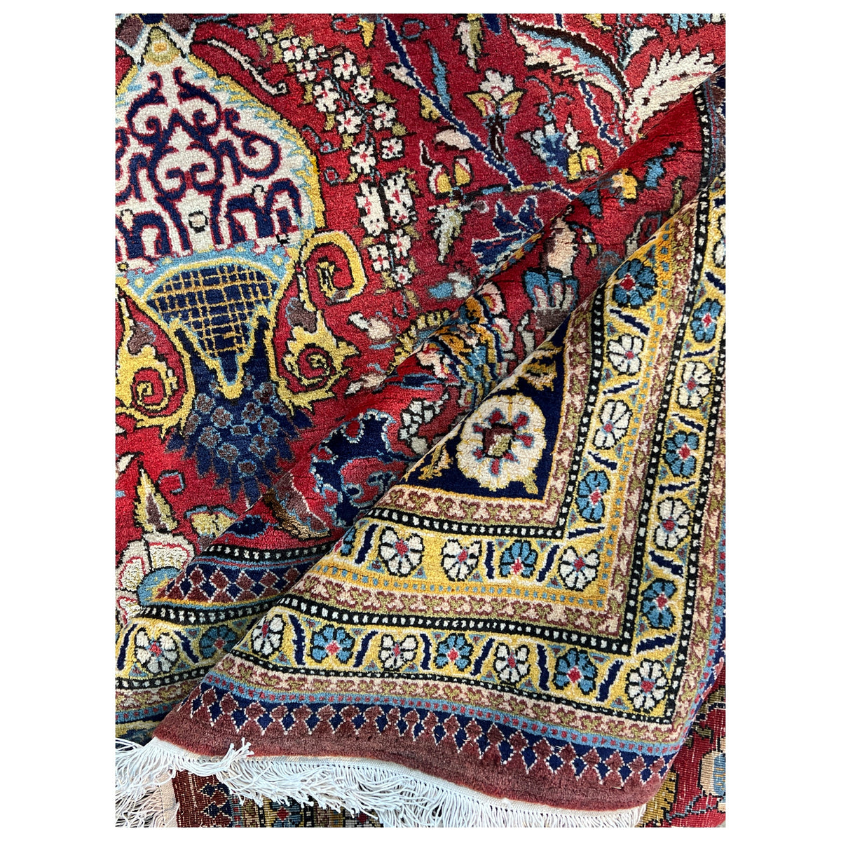 Shahreza carpet close-up: red ornament, blue-gold stripe, and embroidered edges