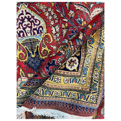 Shahreza carpet close-up: red ornament, blue-gold stripe, and embroidered edges