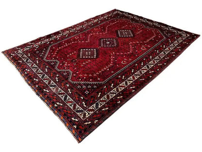 Rug with a red background and geometric diamond shapes, multicolored border lines, diagonal