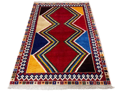 Rectangular Shiraz rug with a central diamond motif in red, blue, and beige, as well as a colorful border.