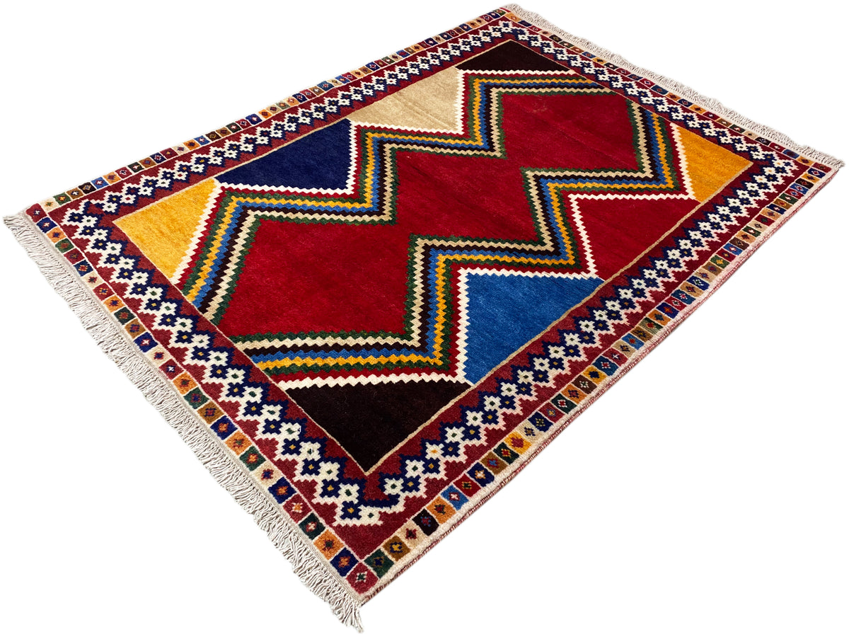 Square Shiraz rug with a zigzag design in red, blue, beige, and multicolored borders, with fringes.