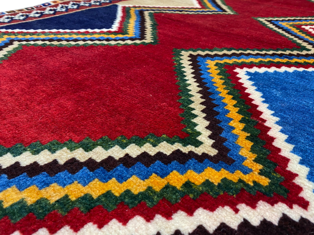 Close-up: Red central motif and colorful zigzag edges of a Shiraz rug, multicolored border.