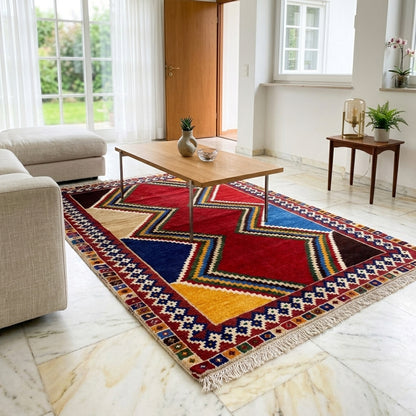 Rectangular Shiraz rug with zigzag and diamond patterns in red, blue, yellow, and beige, fringes.