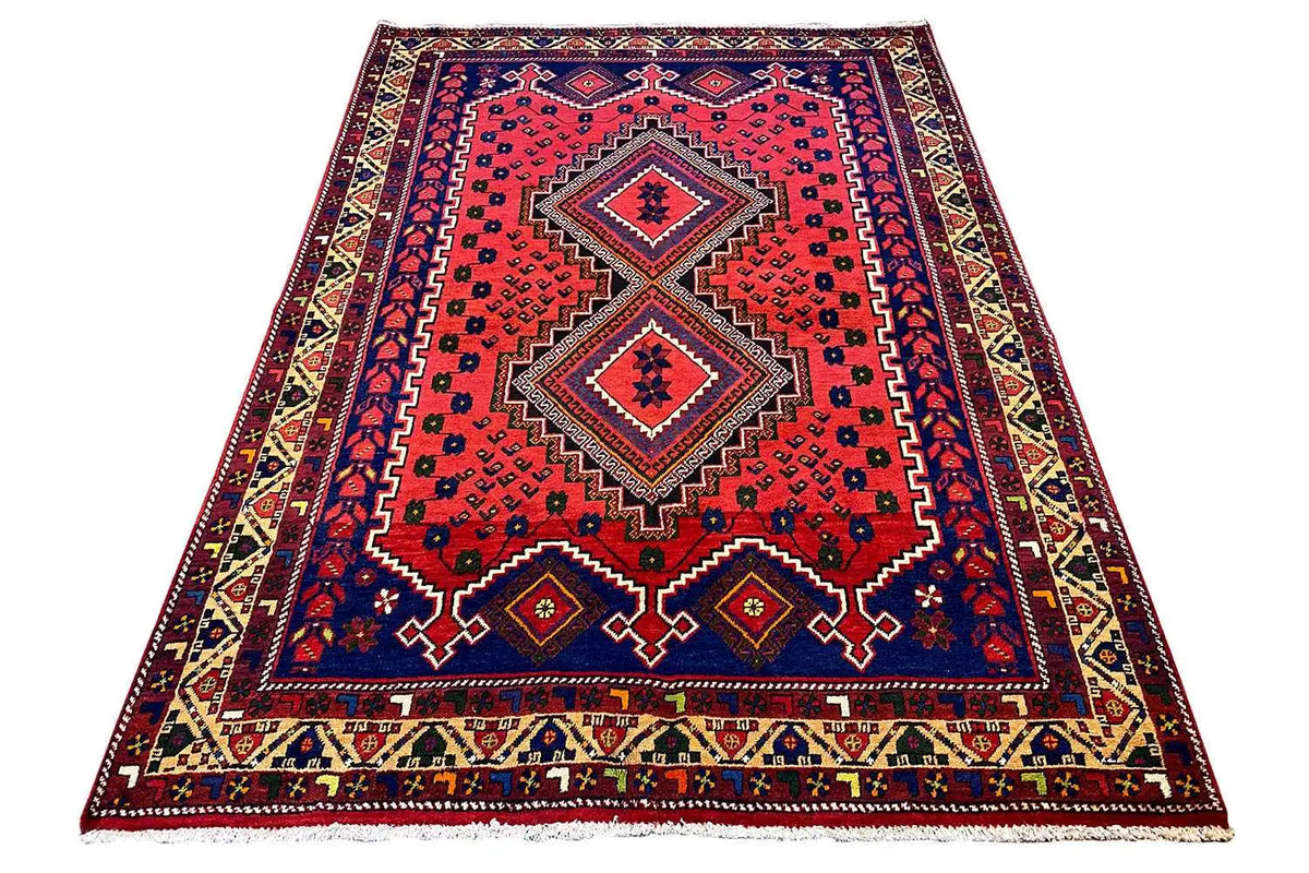 Rectangular rug with a red center, blue border, multicolored ornaments, and fringes