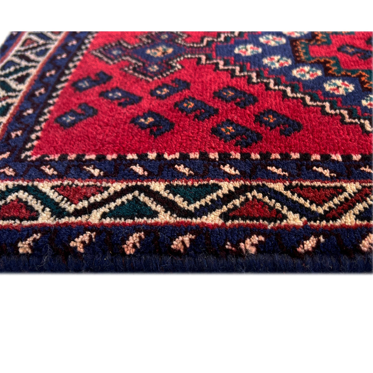 Red runner rug with a pattern in dark blue, cream, and decorative borders
