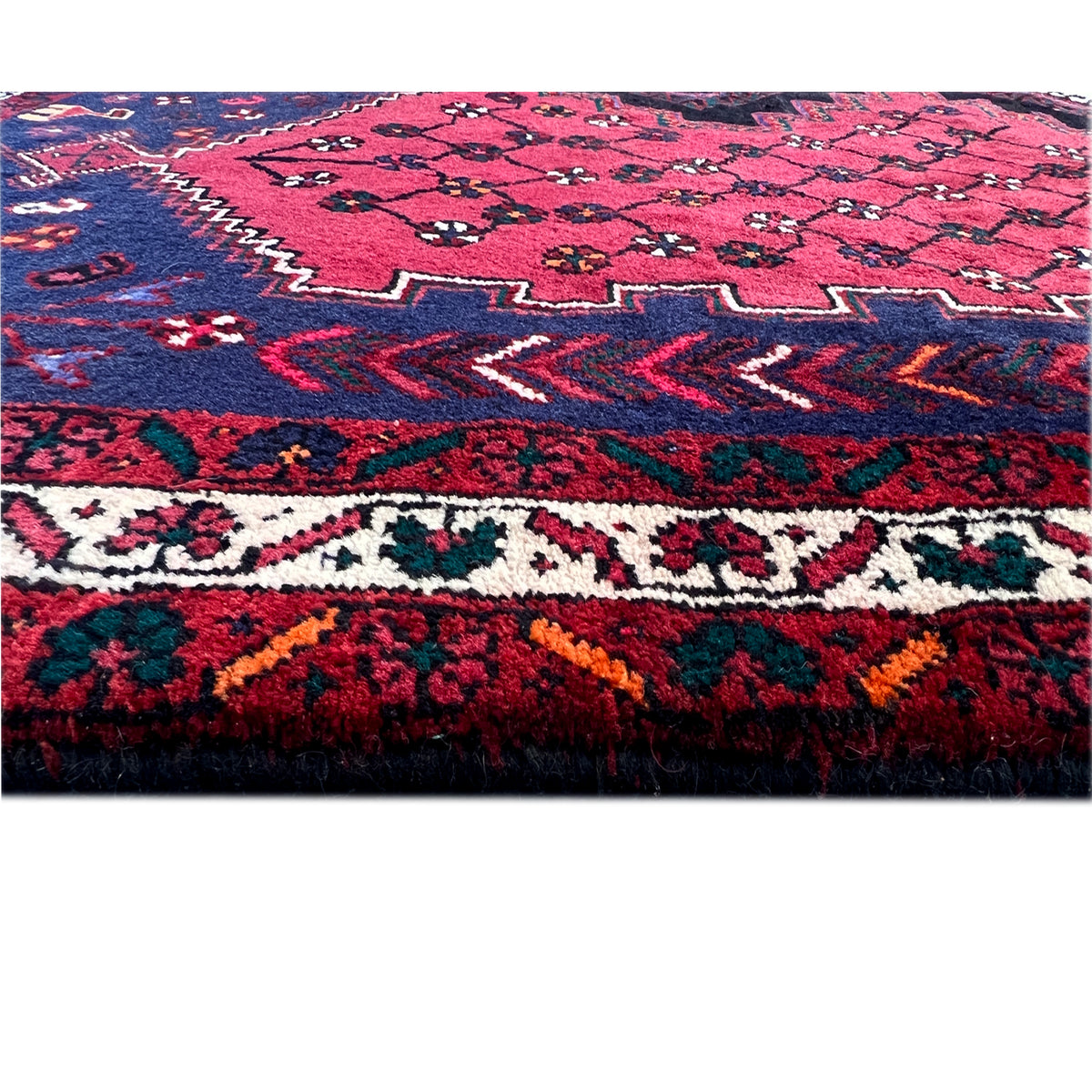 Close-up of carpet fabric: red pattern with dark blue areas and colorful accents