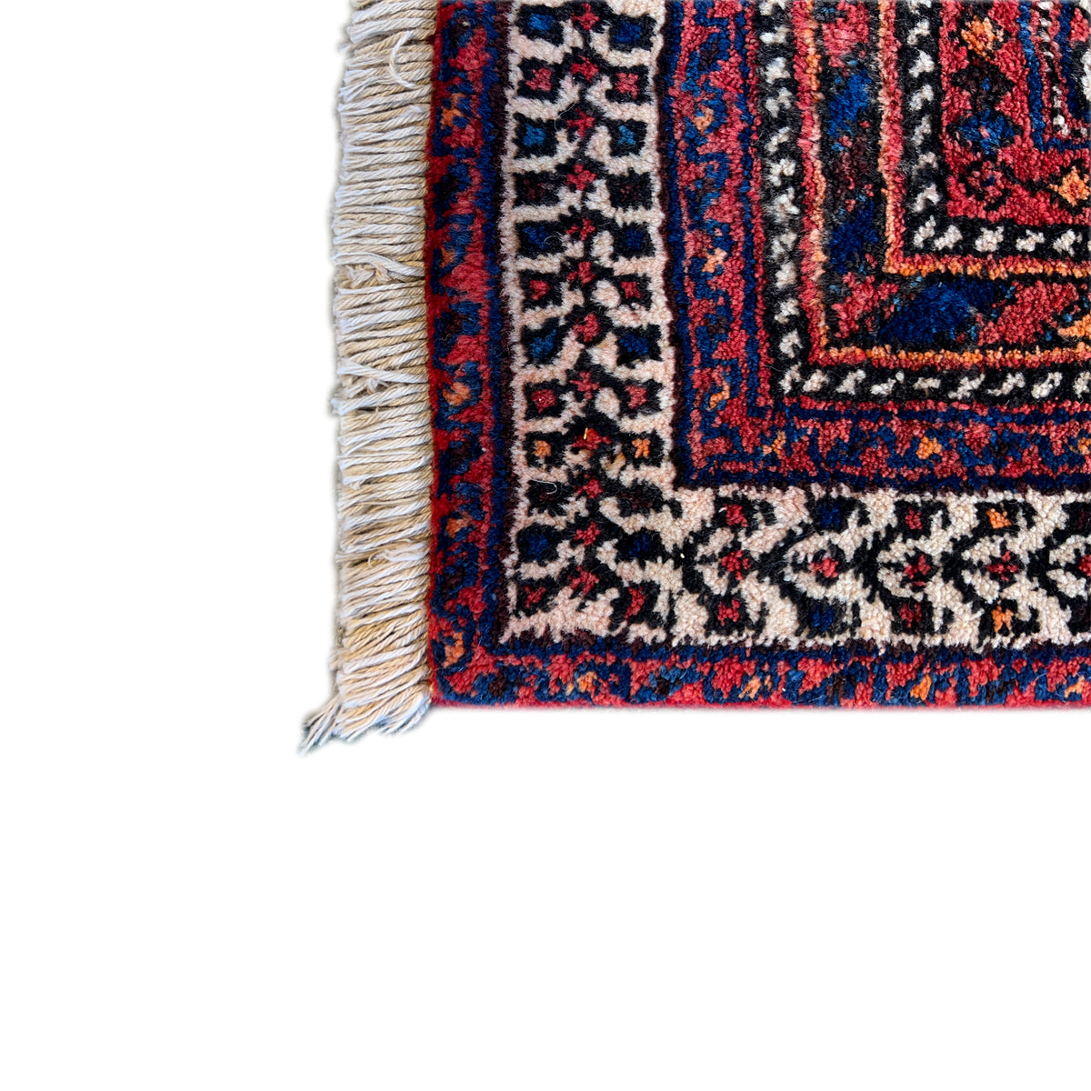 Rug edge with beige fringes and a blue-red ornamental pattern