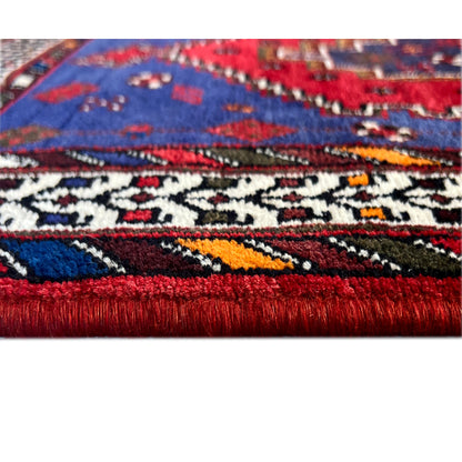Runner rug with a red fringed edge and a geometric pattern in blue and red
