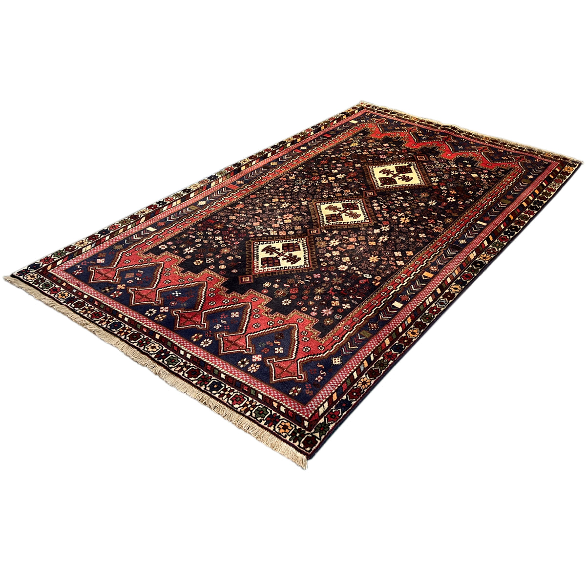 Sirjan rug in three-quarter view with a red border and dark blue field
