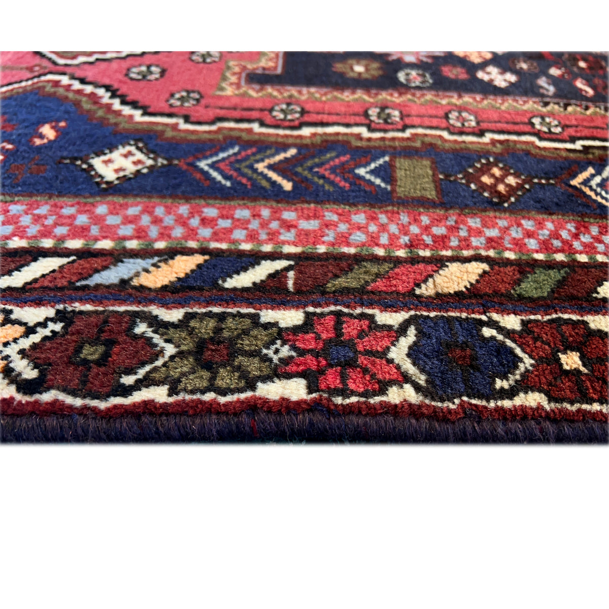 Sirjan carpet close-up: intricate patterns in dark blue, red, and beige, pile edge visible
