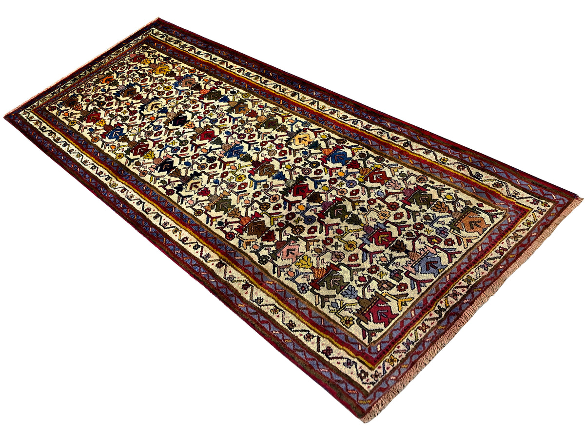 Sirjan carpet positioned diagonally, light-colored surface with colorful symbols and a red border