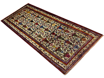 Sirjan carpet positioned diagonally, light-colored surface with colorful symbols and a red border