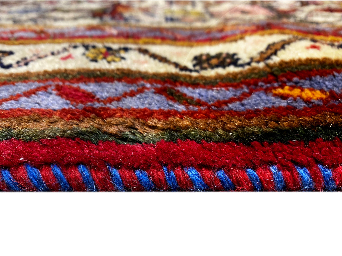 Close-up: rug edge with red and blue fringes and colorful patterned stripes