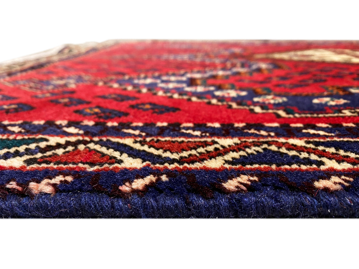 Red runner rug in detail with a multicolored pattern and woven edge