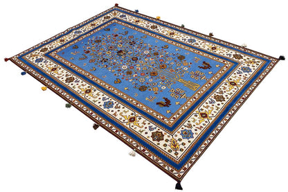 Blue Oriental rug viewed from above, with a patterned border and decorative tassels at the corners