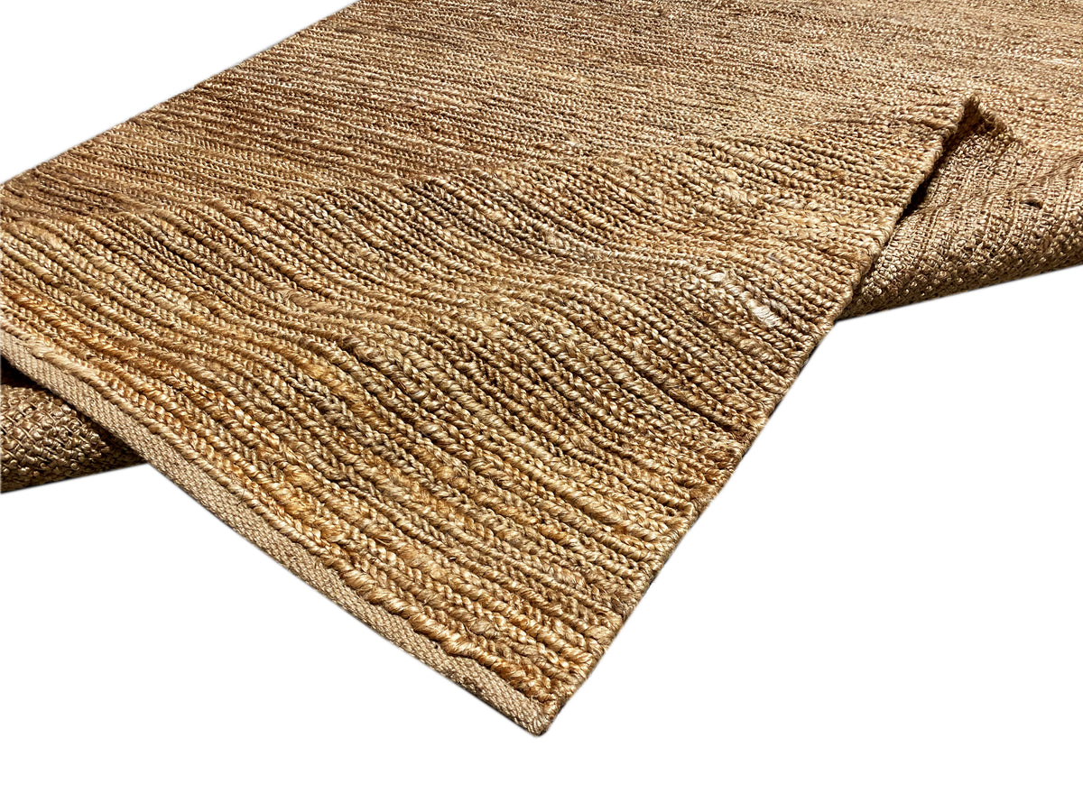 Jute-Teppich in Naturbraun mit sichtbarer Kettel-/Saumkante an der Ecke.