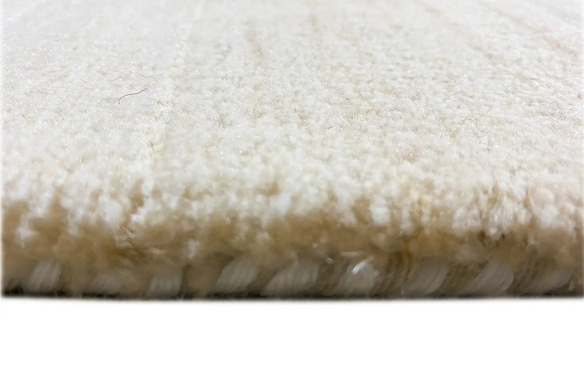 Light-colored rug with dense pile and visible fringe/hem edge