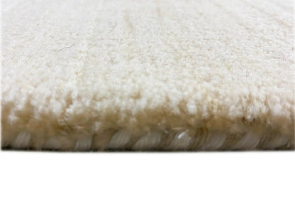 Light-colored rug with dense pile and visible fringe/hem edge