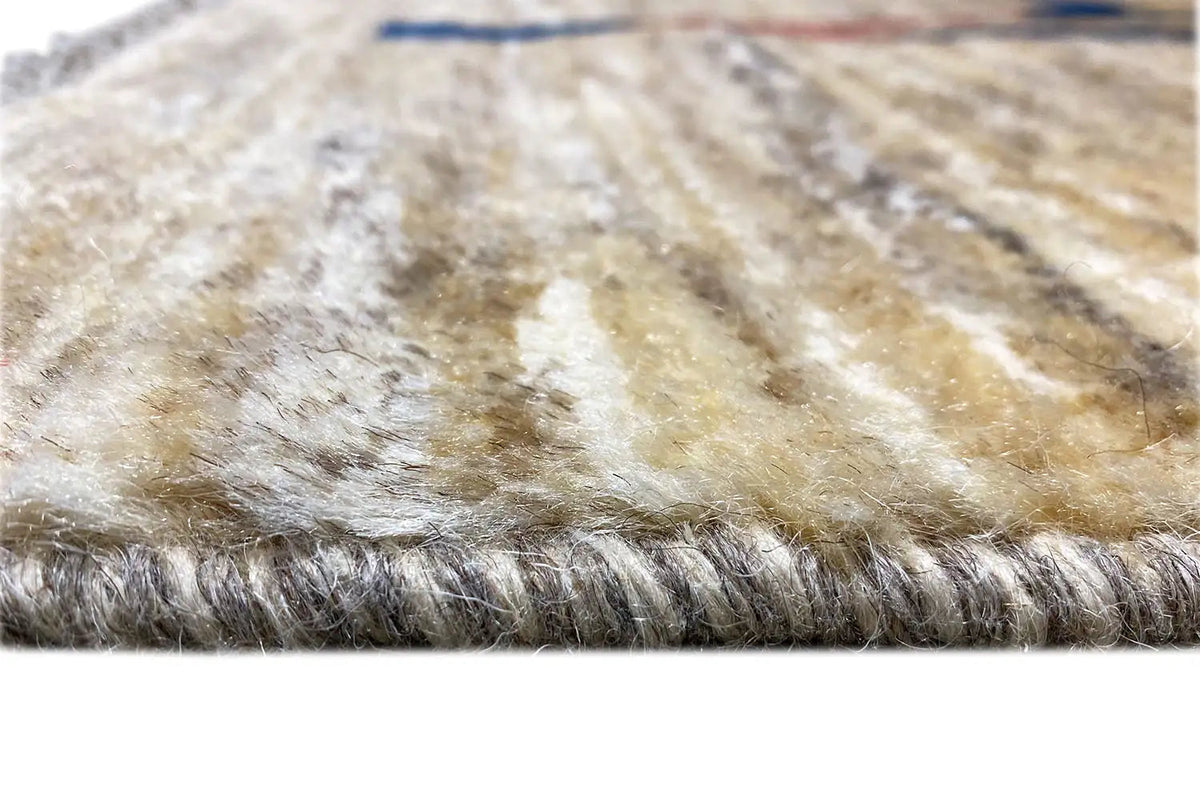 Close-up of a Gabbeh rug: beige pile with fringed edges, fine patterned stripes