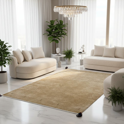 Light brown Gabbeh rug with a white border and blue tassels, spread out over a large area