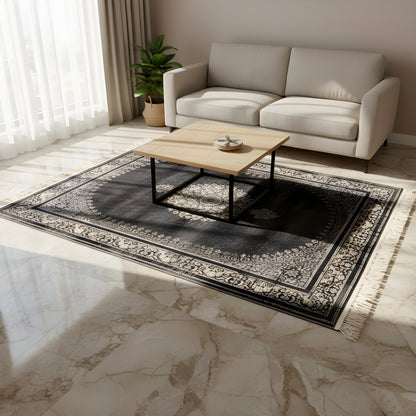Rectangular dark gray medallion rug with a patterned border and fringe on the floor