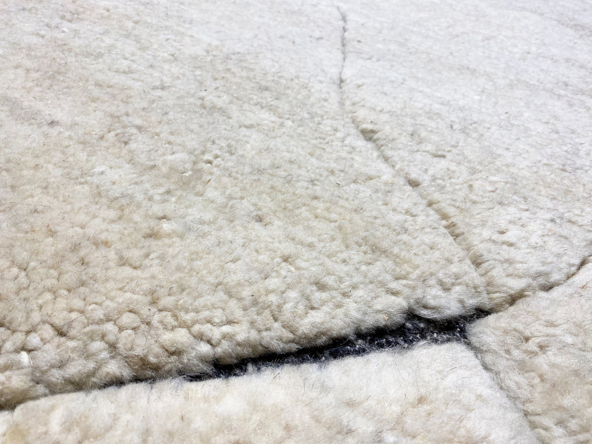 Close-up of the pile surface: cream-colored carpet with a blue border