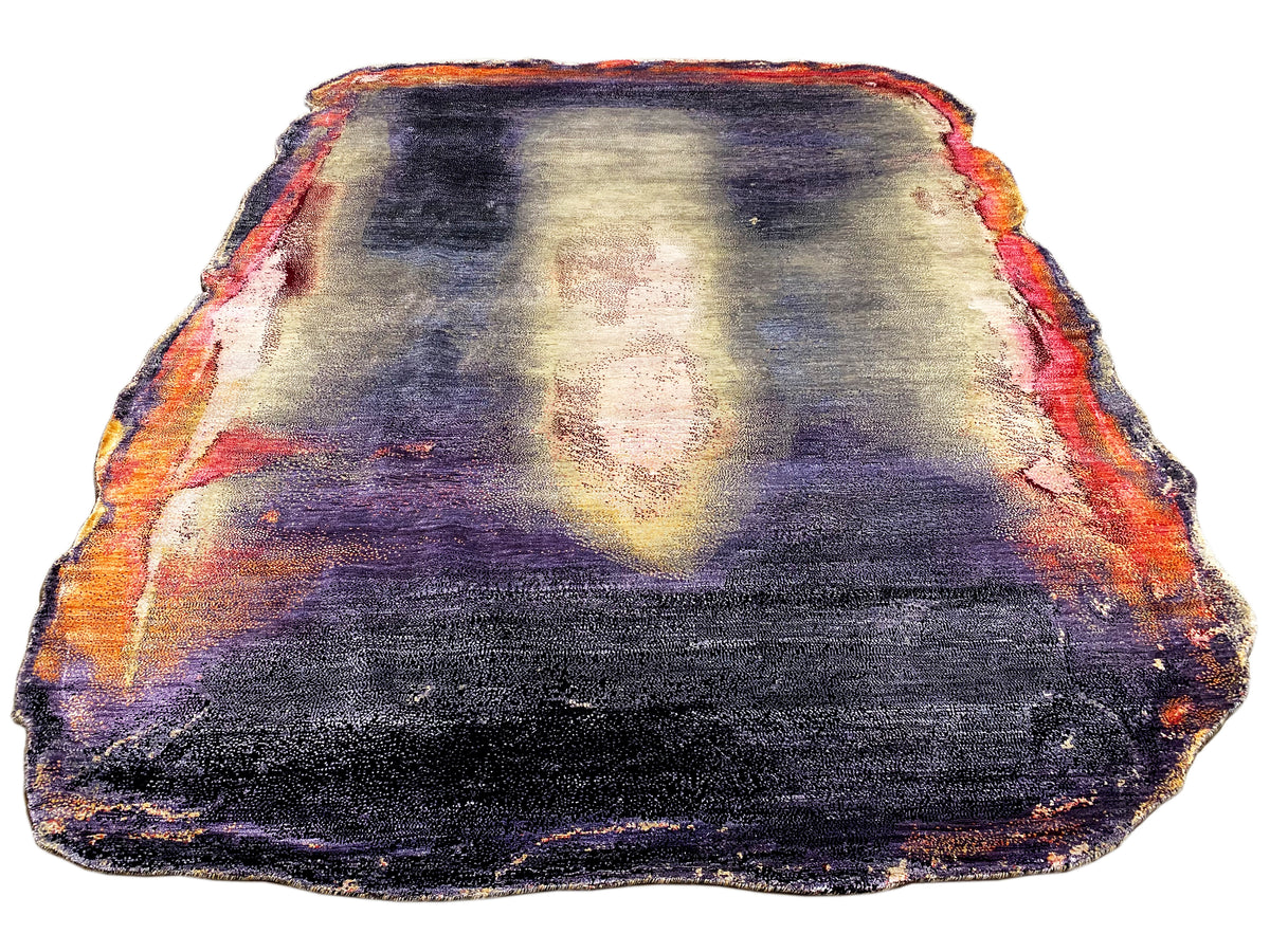 Designer rug with an abstract pattern in dark blue, purple, cream, and orange; bound edge.