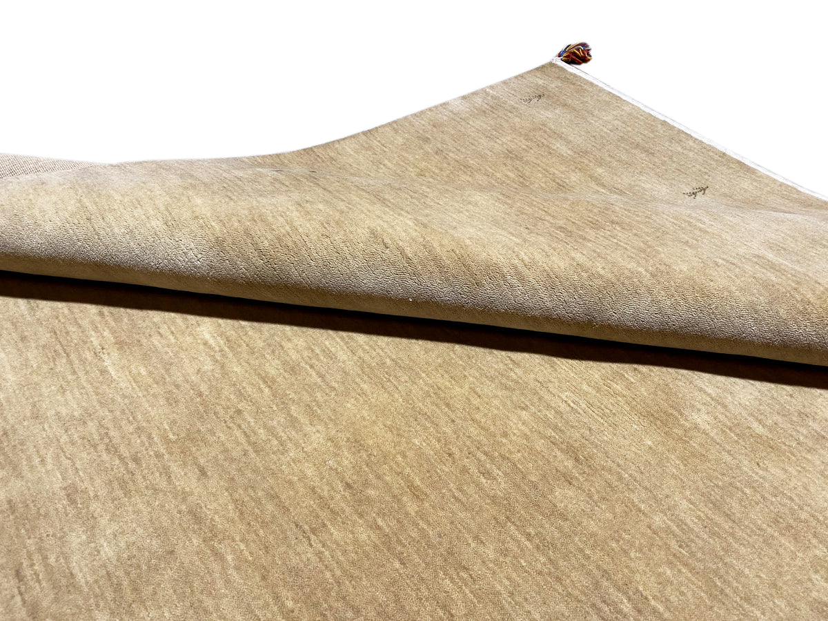Gabbeh rug, light brown, side view, low pile with a white border and tassel at the top