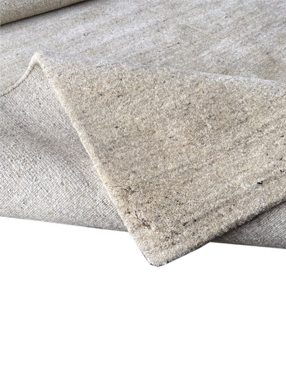 Beige carpet with a rounded corner and a visible selvedge along the edge