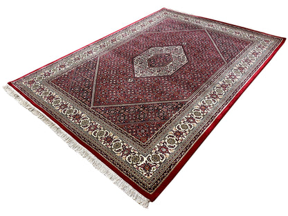 Rectangular red rug with medallion, decorative border, and white fringe along the edge