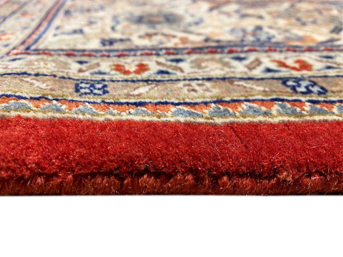 Rug edge with fringe and reddish-brown pile; multicolored decorative border beneath