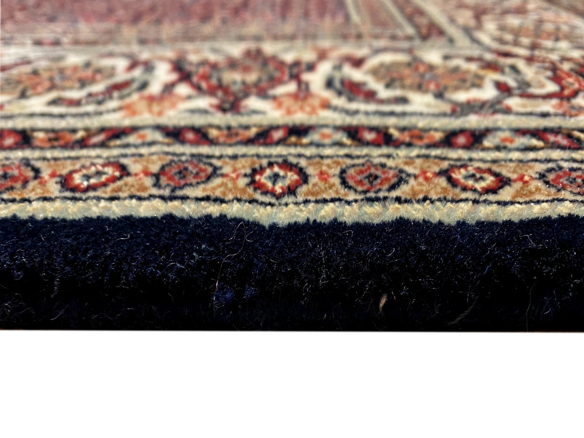Close-up of Bidjar rug: red pattern, dark blue area, and pile with fringes