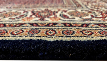 Close-up of Bidjar rug: red pattern, dark blue area, and pile with fringes