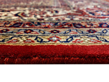 Close-up of a Bidjar rug: dense red pile with colorful patterned lines along the edge