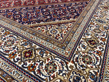 Close-up: carpet with a blue-and-white border, red panels, and intricate ornaments