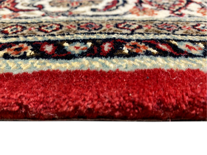 Close-up of a Bidjar rug: reddish-brown pile surface with a multicolored border ornament