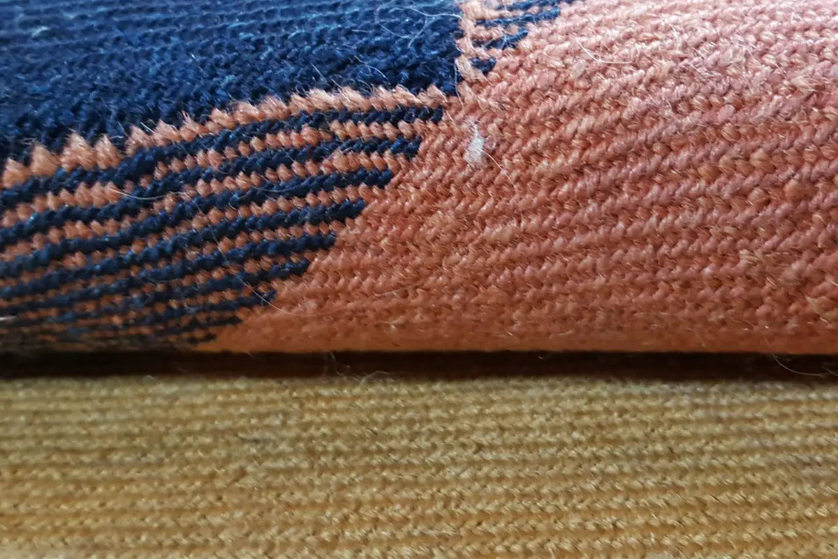 Close-up of a rug edge with fringes and woven texture, blue-yellow stripes on terracotta