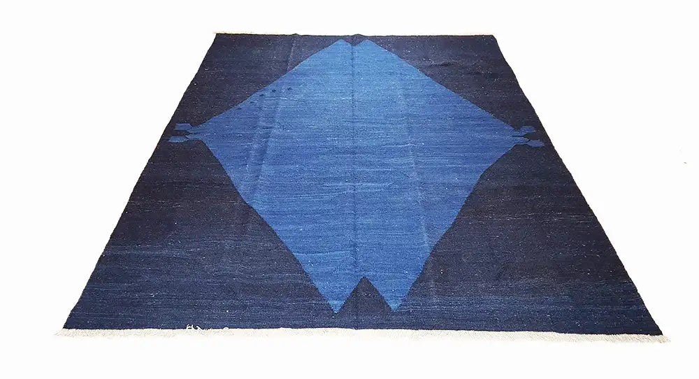 Rectangular rug with a dark blue background and a large blue diamond pattern