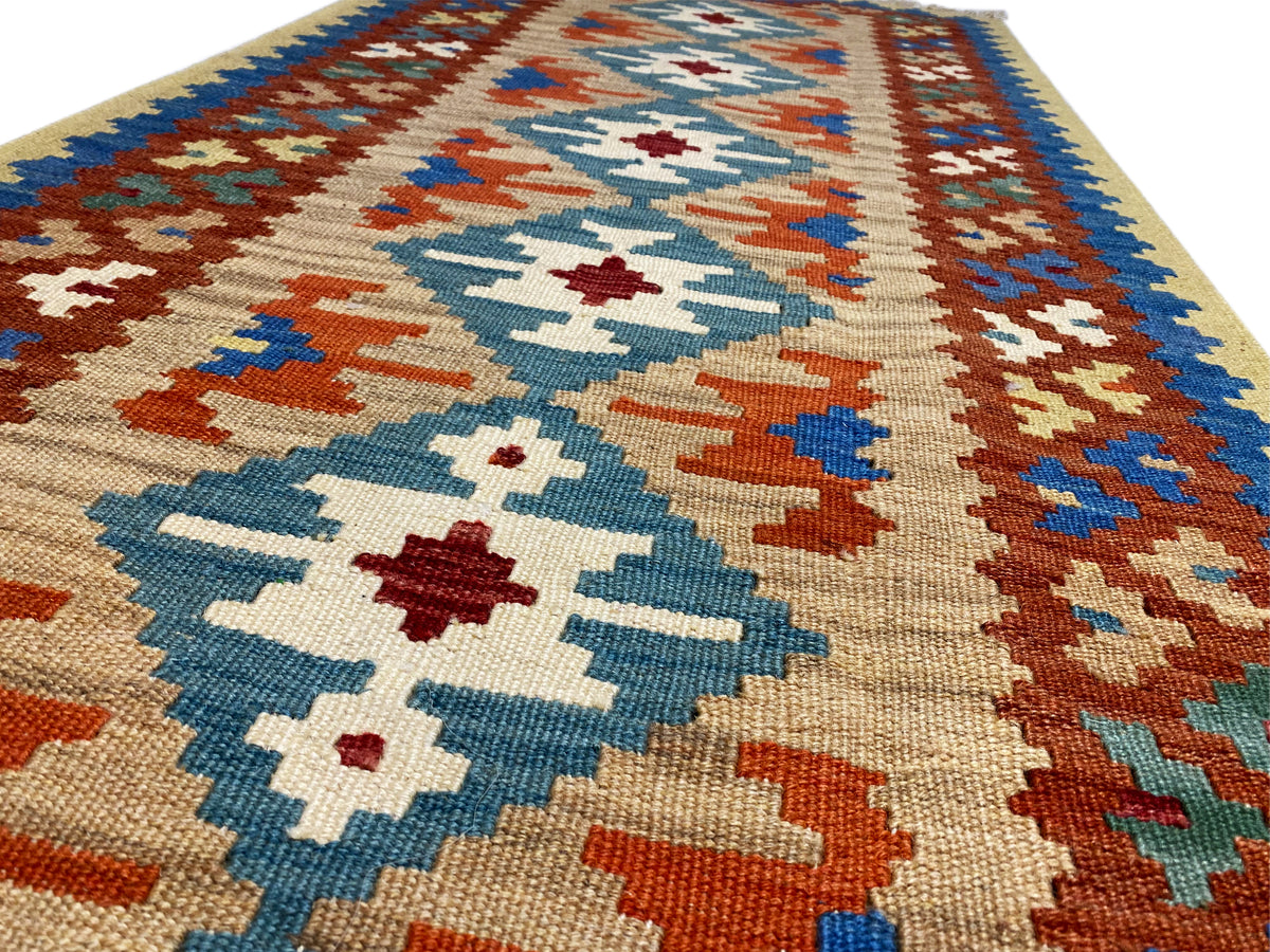 Kilim rug detail: diamond and cross motifs in blue, orange, green and cream