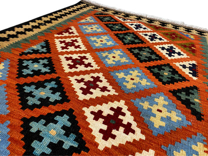 Colorful kilim rug with a geometric pattern of diamonds and cross shapes, dark border