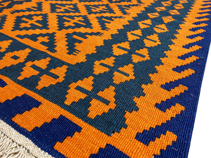 Kilim rug with an orange-yellow and dark blue woven pattern, close-up