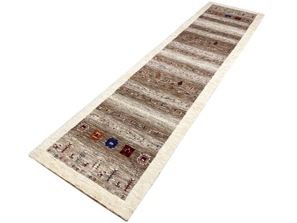 Gabbeh runner rug viewed from above at an angle: light border, gray-brown pattern with color accents
