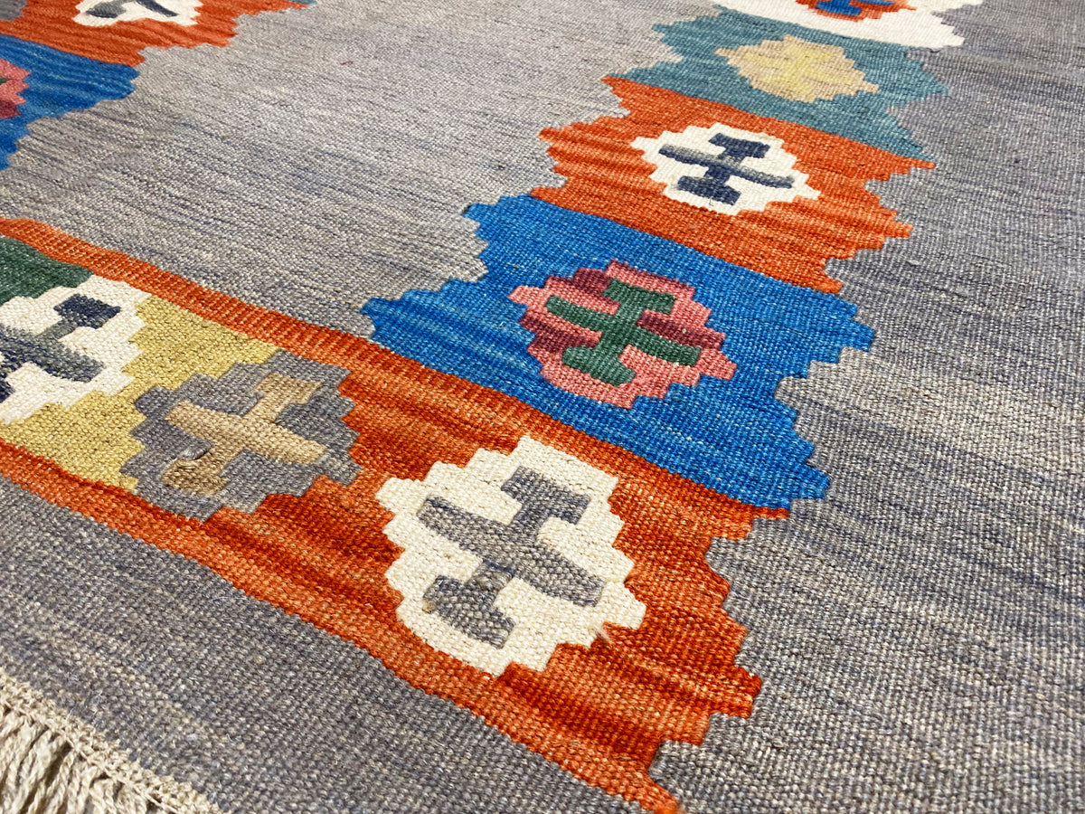Detailed view: gray mélange kilim rug with a colorful diamond pattern in orange and blue