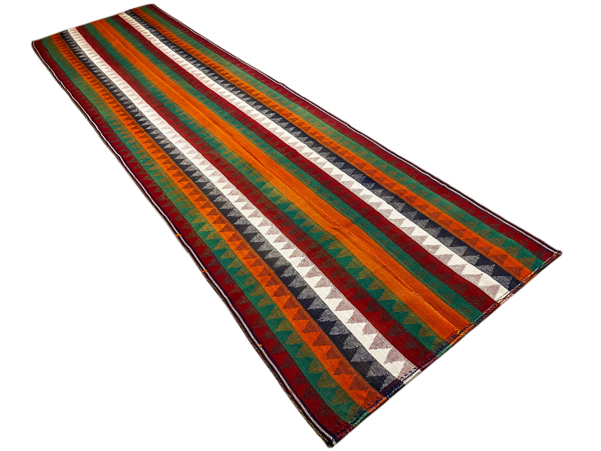 Jajim runner rug at an angle: multicolored zigzag stripes, bound edge