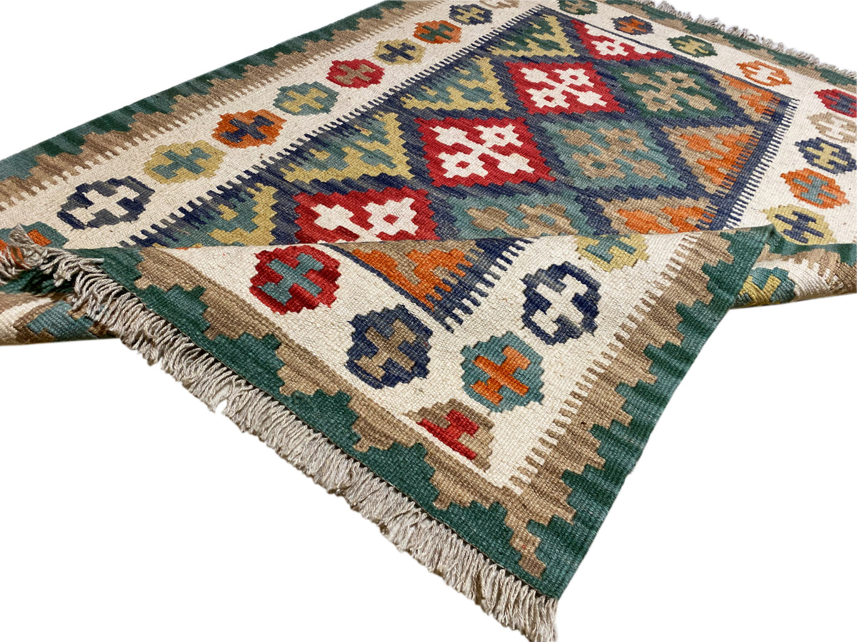 Kilim rug with diagonal diamond patterns in green, white, and red, with fringes