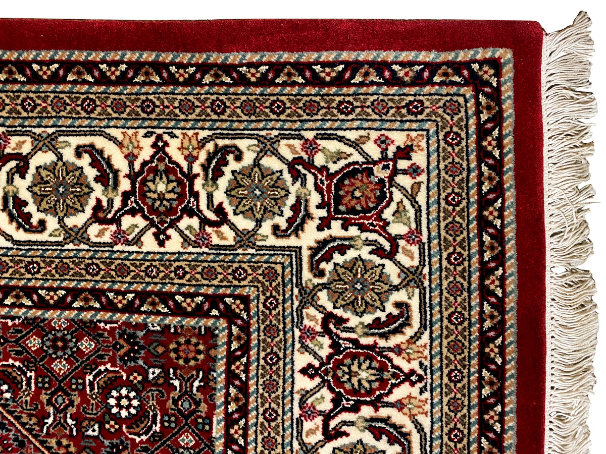 Carpet detail with a red ground, multicolored border, and woven edge