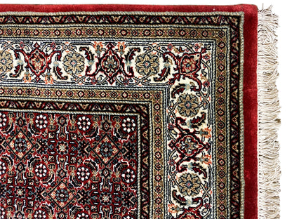 Bidjar rug corner with fringes: cream-colored motifs on a dark red background